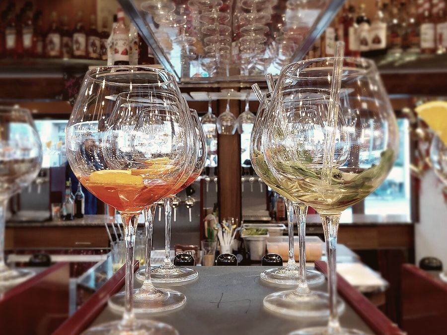 Calici di spritz sul bancone, davanti alle bottiglie